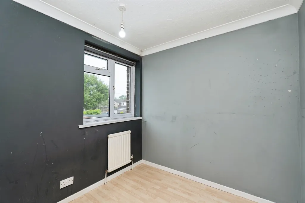 A compact third bedroom ideal as a nursery, office, or guest room, with front-facing window and laminate flooring.