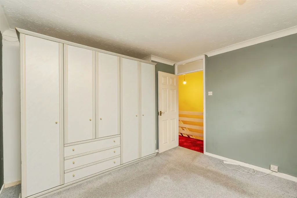 Double bedroom with fitted wardrobes, grey carpet, and neutral green tones.