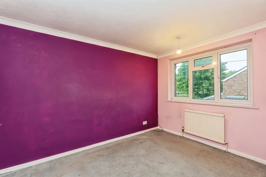 Bedroom with pink and purple walls, carpeted floor, and a rear window.